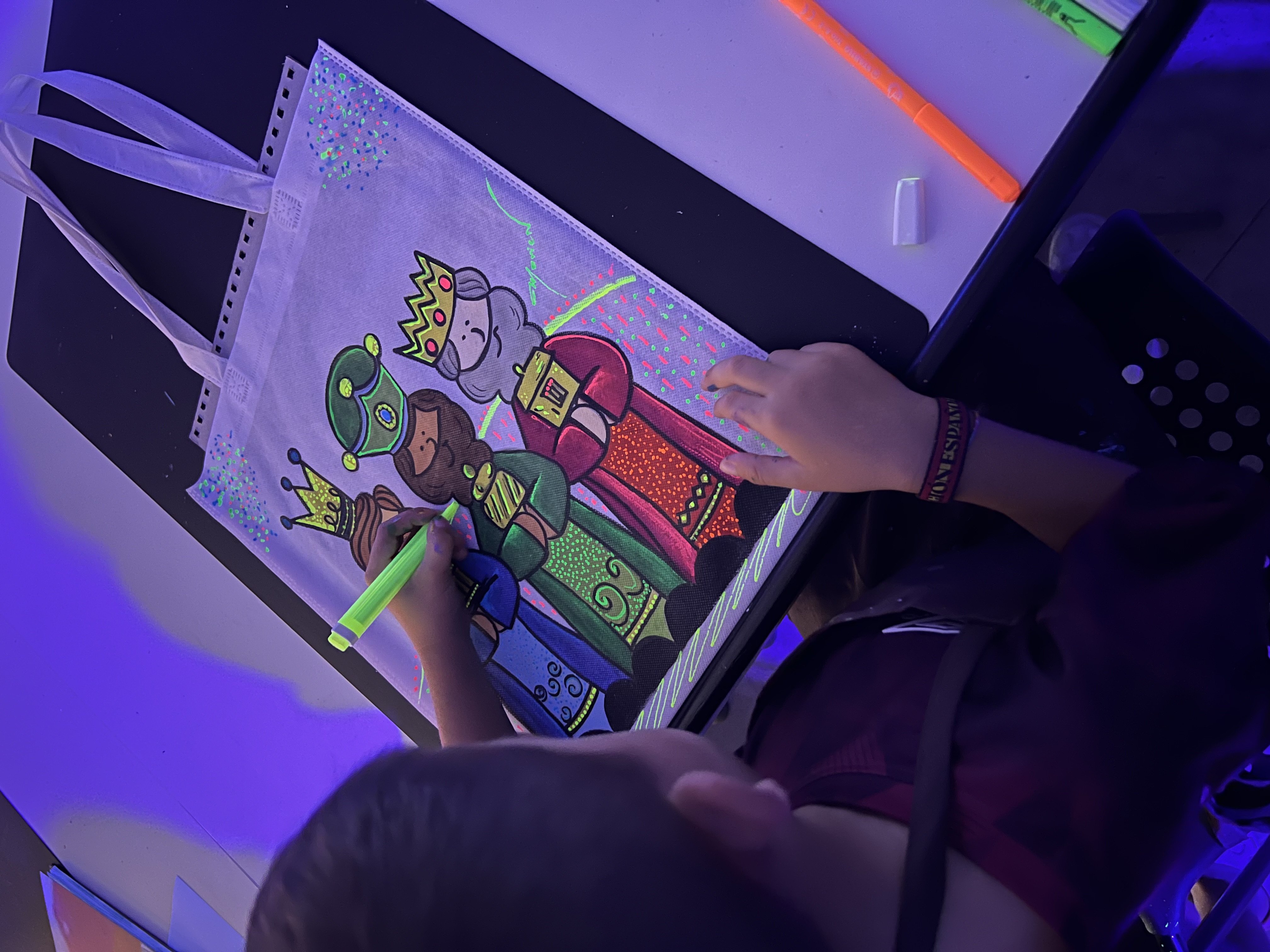Participante creando una bolsa de Reyes con pintura neón